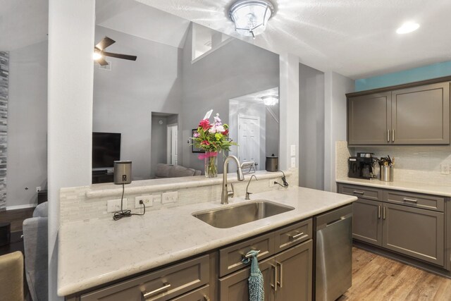 kitchen with tasteful backsplash, dishwasher, lofted ceiling, sink, and light hardwood / wood-style floors