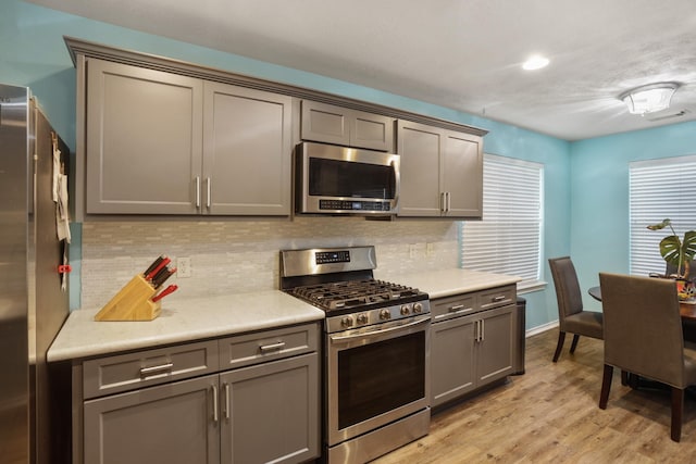 kitchen featuring tasteful backsplash, appliances with stainless steel finishes, light hardwood / wood-style floors, and gray cabinetry