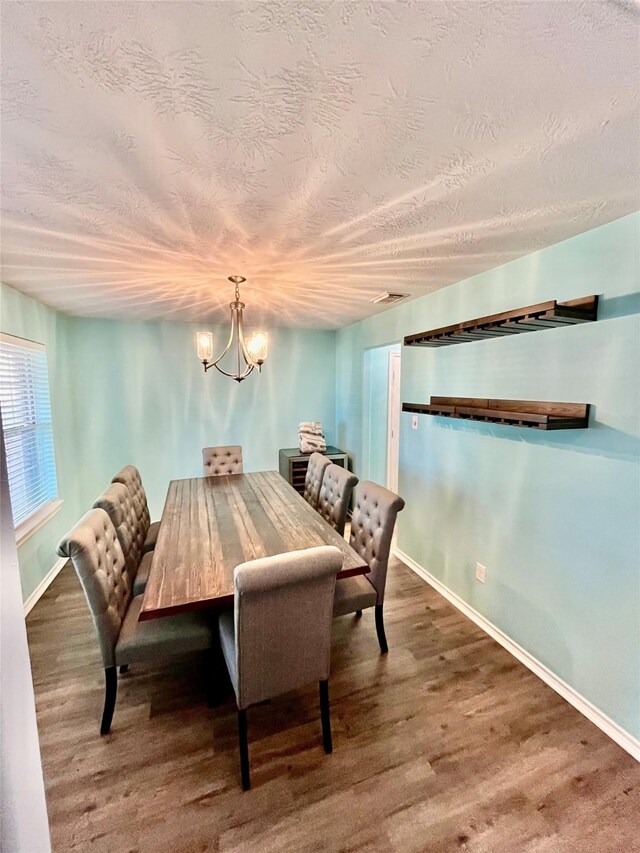 dining area featuring an inviting chandelier, dark wood-type flooring, and a textured ceiling