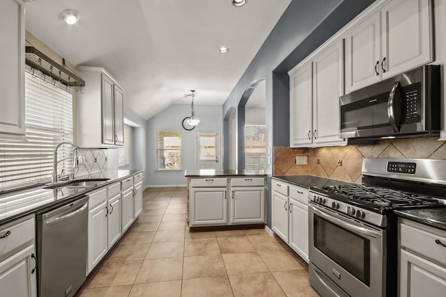 kitchen with hanging light fixtures, sink, vaulted ceiling, appliances with stainless steel finishes, and white cabinetry