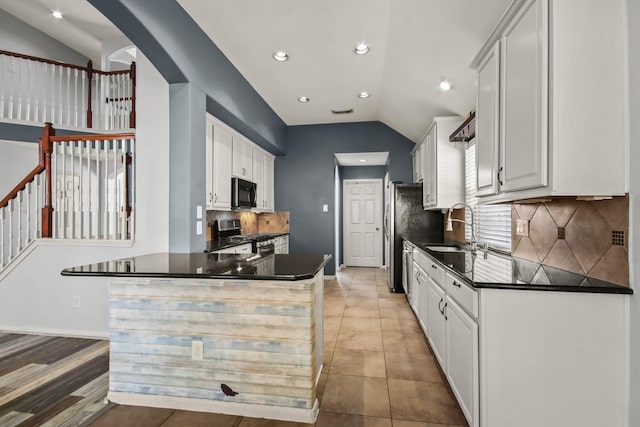 kitchen with tasteful backsplash, sink, white cabinets, stainless steel stove, and lofted ceiling