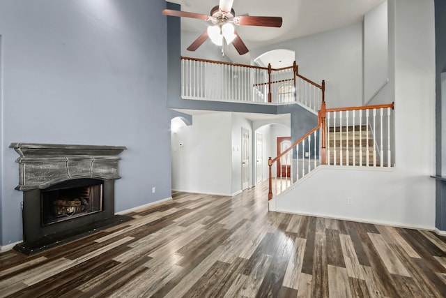 unfurnished living room featuring a high ceiling, hardwood / wood-style flooring, and ceiling fan