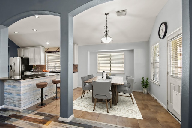 tiled dining room with a wealth of natural light and vaulted ceiling