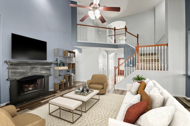 living room featuring wood-type flooring, ceiling fan, and a high ceiling