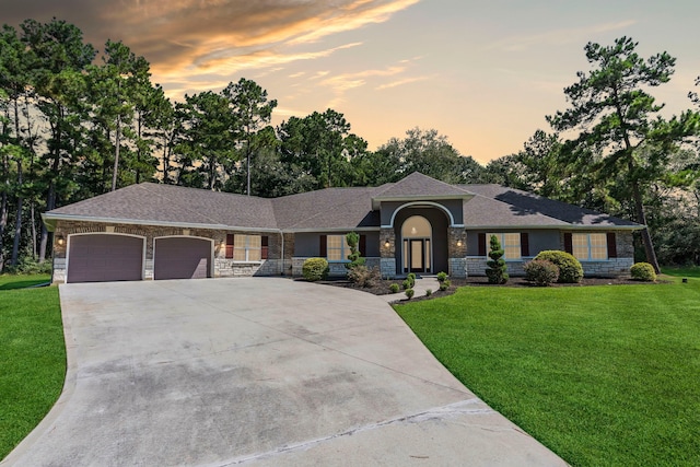 ranch-style home featuring a garage and a yard