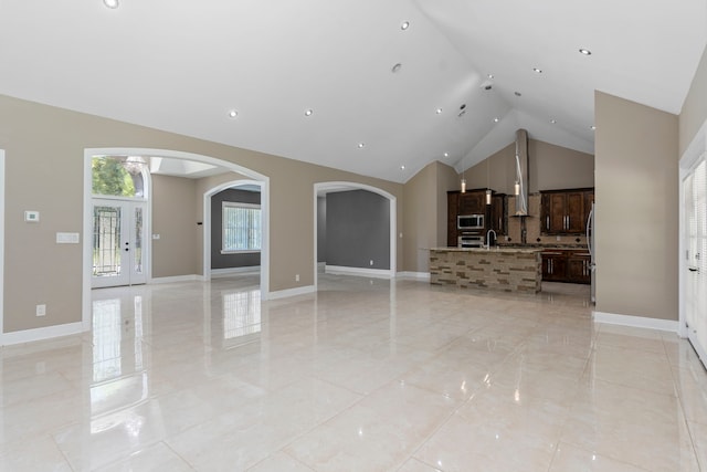 unfurnished living room featuring high vaulted ceiling, french doors, and sink