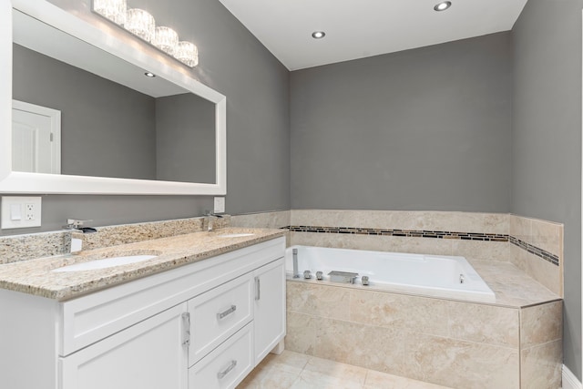 bathroom with tiled bath, vanity, and tile patterned flooring