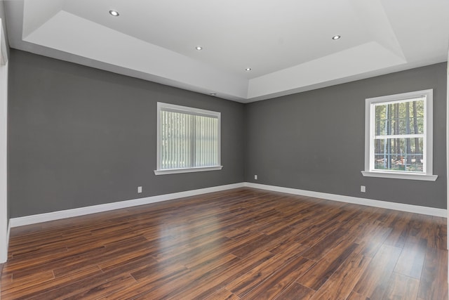 empty room with dark wood-type flooring and a raised ceiling