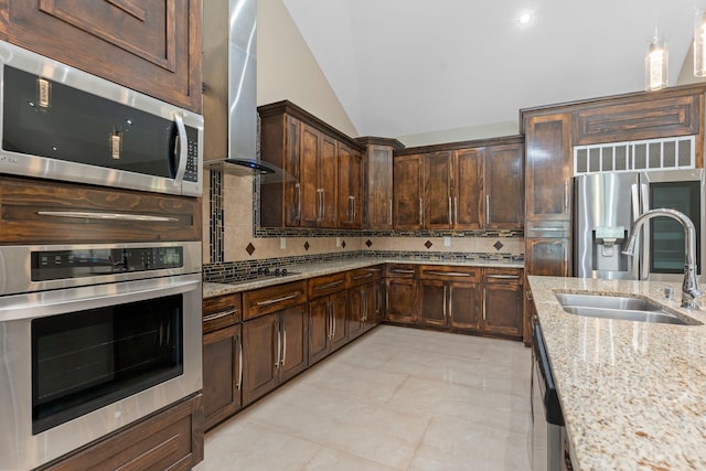 kitchen featuring appliances with stainless steel finishes, extractor fan, sink, vaulted ceiling, and light stone counters