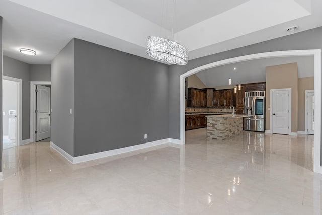 unfurnished living room with sink and an inviting chandelier