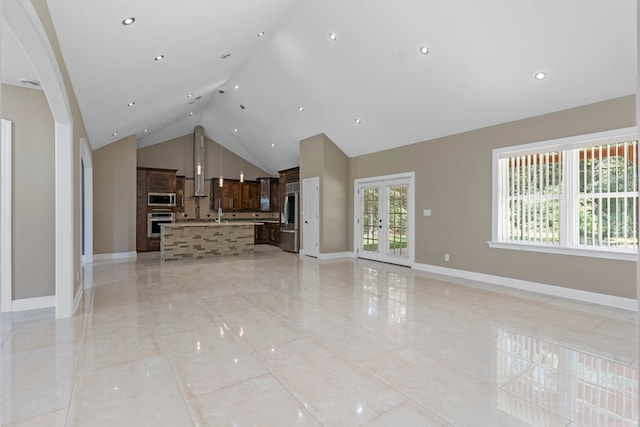 unfurnished living room featuring high vaulted ceiling, french doors, and plenty of natural light