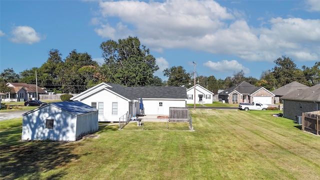 rear view of property with an outbuilding, roof with shingles, a lawn, a residential view, and a storage unit