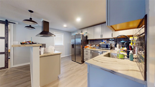 kitchen with ventilation hood, stainless steel appliances, sink, pendant lighting, and a barn door