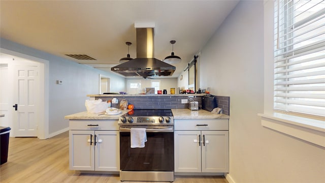 kitchen featuring stainless steel electric stove, island range hood, white cabinets, and light wood-type flooring