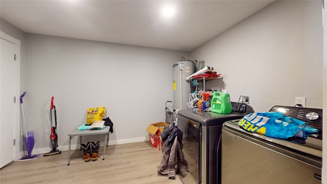 laundry room featuring washing machine and dryer, light hardwood / wood-style flooring, and water heater