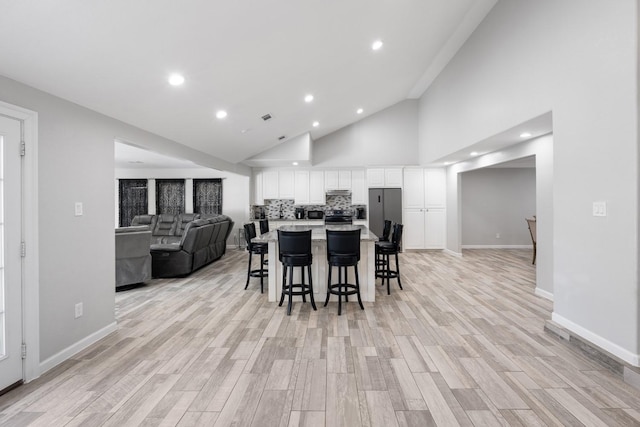 dining space with light hardwood / wood-style floors and high vaulted ceiling