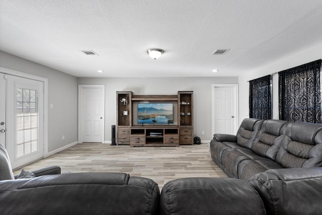 living room featuring french doors, a textured ceiling, and light hardwood / wood-style floors