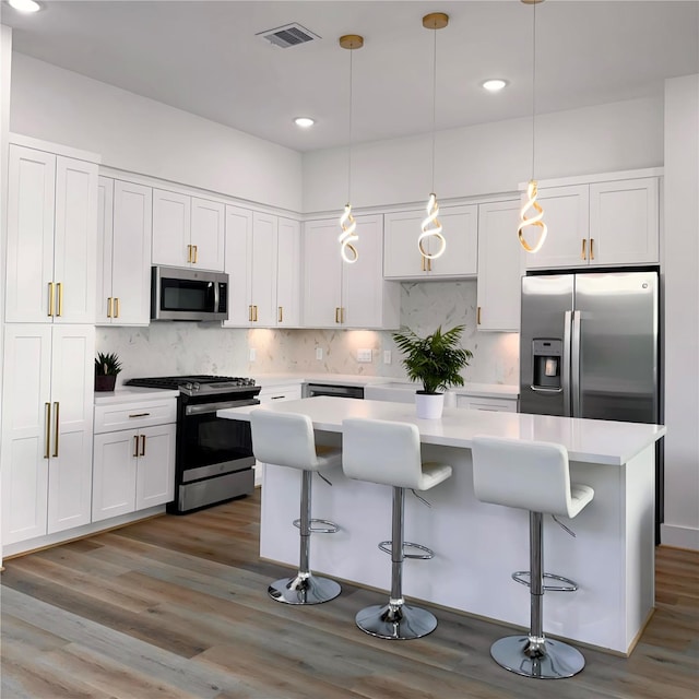 kitchen featuring white cabinets, a breakfast bar, stainless steel appliances, and a kitchen island