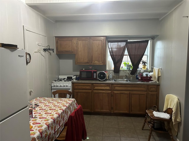 kitchen with white appliances, dark tile patterned floors, and sink