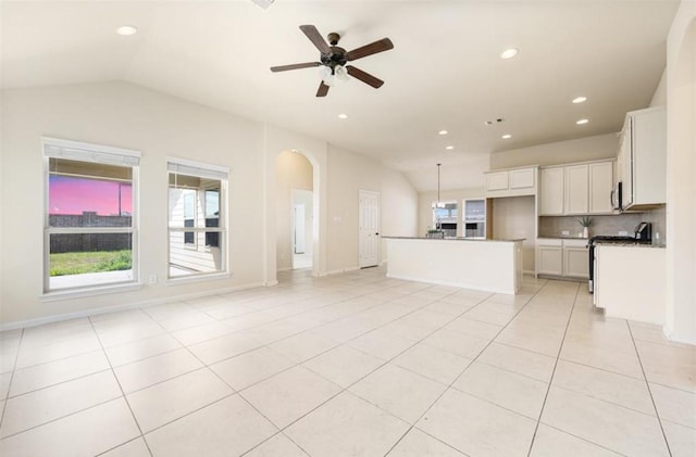 unfurnished living room with ceiling fan, light tile patterned flooring, and vaulted ceiling