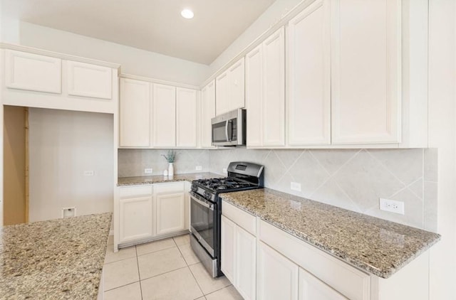 kitchen with light stone countertops, white cabinets, stainless steel appliances, and light tile patterned floors