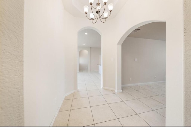 hallway with a chandelier and light tile patterned floors