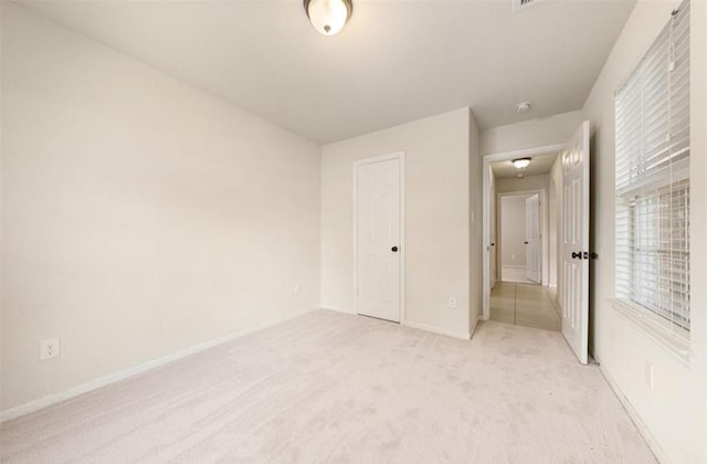 unfurnished bedroom featuring light carpet and a closet