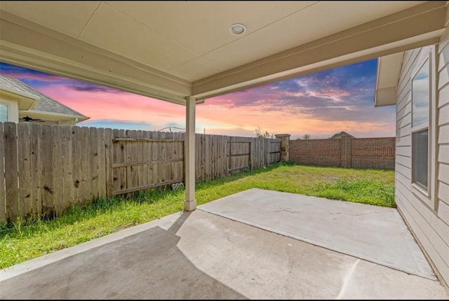 patio terrace at dusk featuring a yard