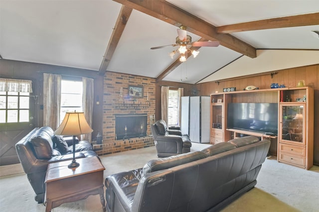 carpeted living room featuring vaulted ceiling with beams, a brick fireplace, ceiling fan, and wood walls