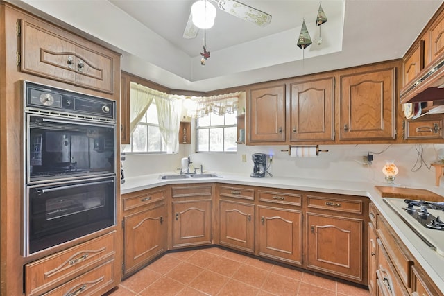 kitchen featuring sink, a raised ceiling, white gas stovetop, black double oven, and light tile patterned floors