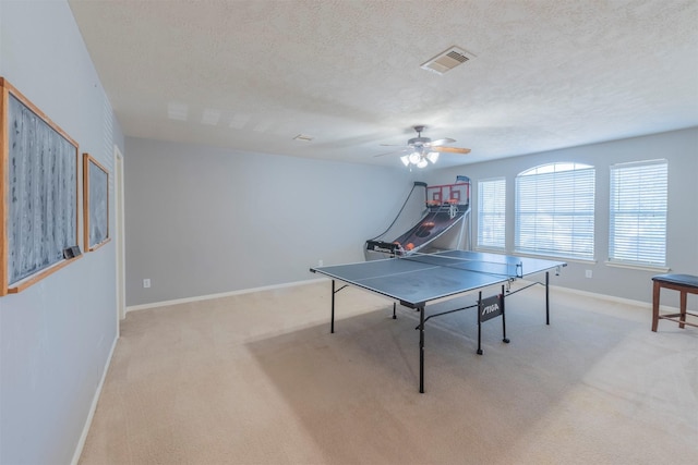 recreation room featuring ceiling fan, light colored carpet, and a textured ceiling