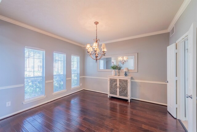 spare room featuring a chandelier, ornamental molding, and dark wood-type flooring