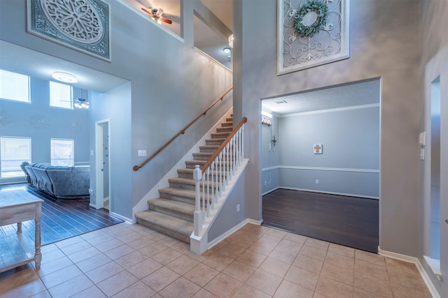 tiled foyer with a high ceiling, a wealth of natural light, ornamental molding, and ceiling fan