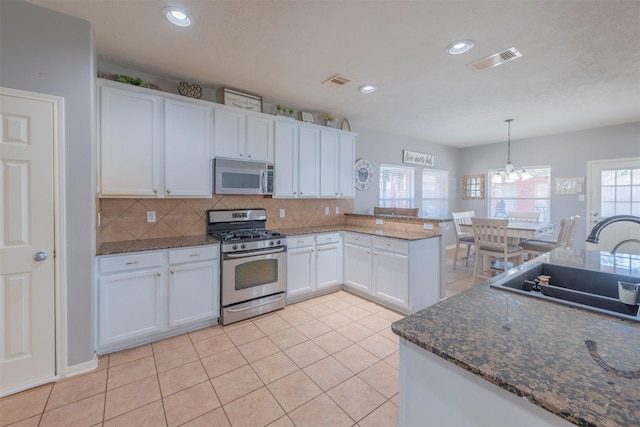 kitchen with sink, stainless steel range with gas cooktop, a notable chandelier, pendant lighting, and white cabinets