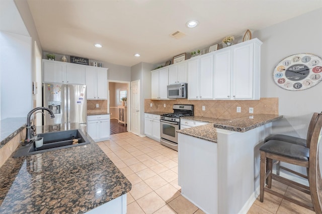 kitchen with white cabinets, sink, light tile patterned floors, appliances with stainless steel finishes, and kitchen peninsula