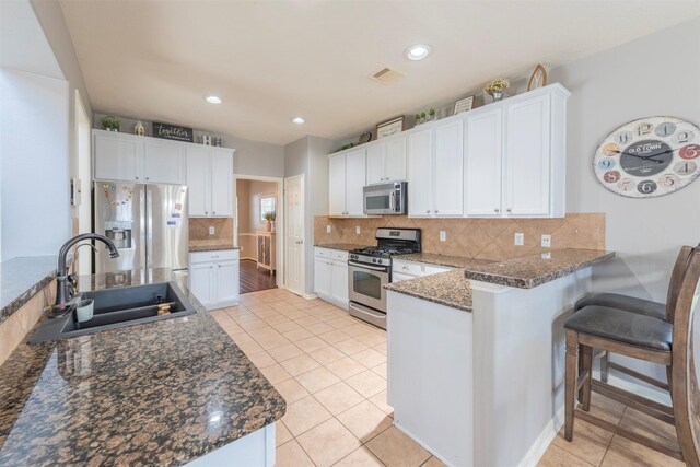 kitchen with white cabinetry, sink, light tile patterned floors, kitchen peninsula, and stainless steel appliances