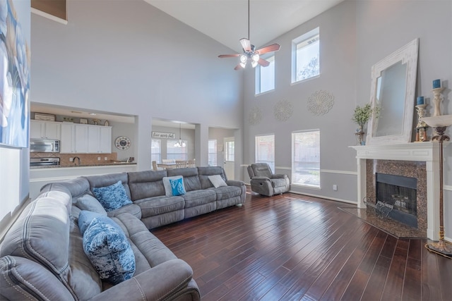 living room with dark wood-type flooring, ceiling fan, plenty of natural light, and a high end fireplace