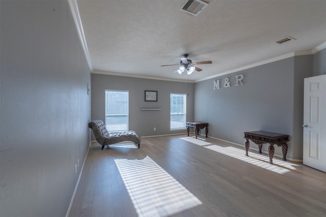 living area featuring hardwood / wood-style flooring, ceiling fan, crown molding, and a textured ceiling