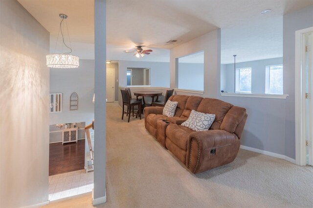 living room featuring ceiling fan with notable chandelier and carpet floors