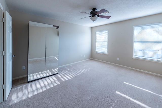 unfurnished bedroom featuring ceiling fan, a closet, carpet floors, and a textured ceiling