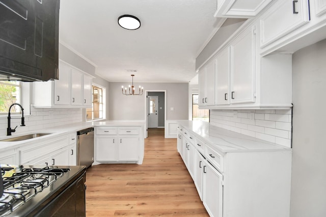 kitchen featuring an inviting chandelier, sink, stainless steel dishwasher, decorative light fixtures, and white cabinetry