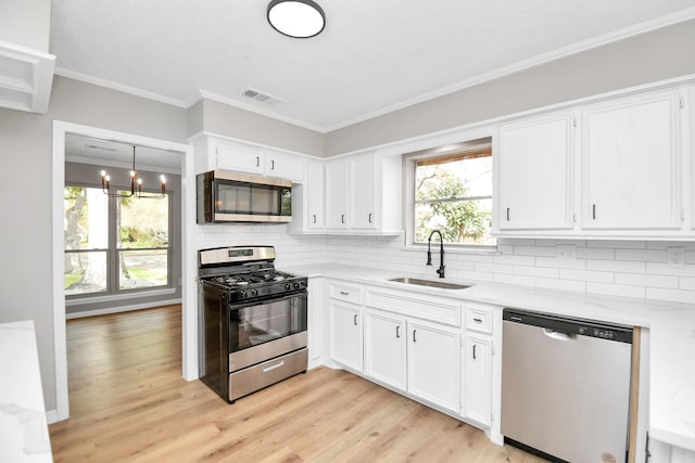 kitchen featuring white cabinets, sink, appliances with stainless steel finishes, and an inviting chandelier