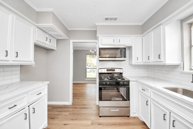 kitchen featuring white cabinets, decorative backsplash, light stone counters, and stainless steel appliances