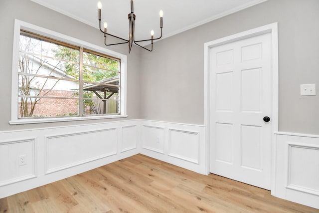 unfurnished dining area with a healthy amount of sunlight, light hardwood / wood-style floors, ornamental molding, and an inviting chandelier