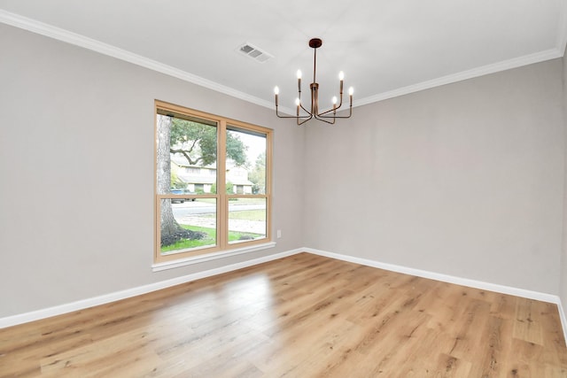 empty room featuring a notable chandelier, light wood-type flooring, and crown molding