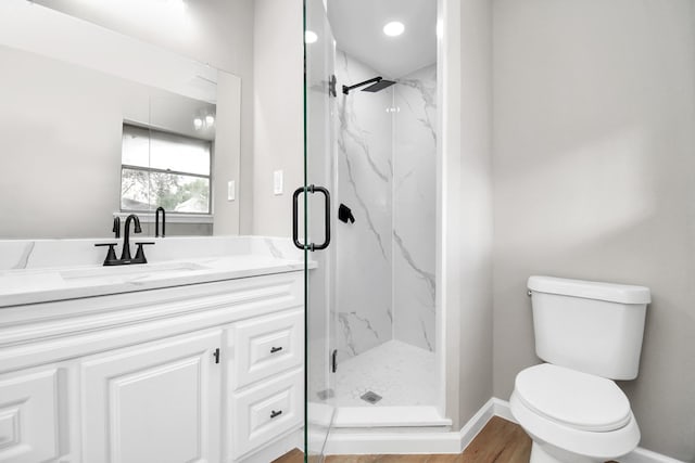 bathroom with wood-type flooring, vanity, a shower with shower door, and toilet