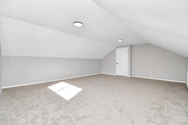 additional living space with carpet flooring and lofted ceiling