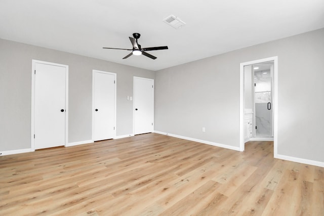 unfurnished bedroom featuring ensuite bathroom, ceiling fan, light hardwood / wood-style floors, and two closets