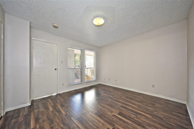 spare room featuring a textured ceiling and dark hardwood / wood-style floors