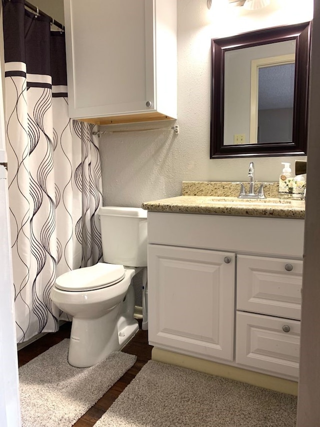 bathroom with hardwood / wood-style flooring, vanity, and toilet